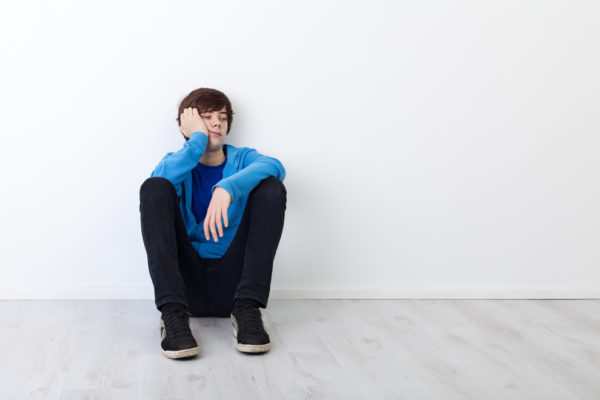 I am not in the mood today - bored teenager boy sitting by the wall