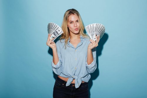 Beautiful young blonde woman holding money in hands