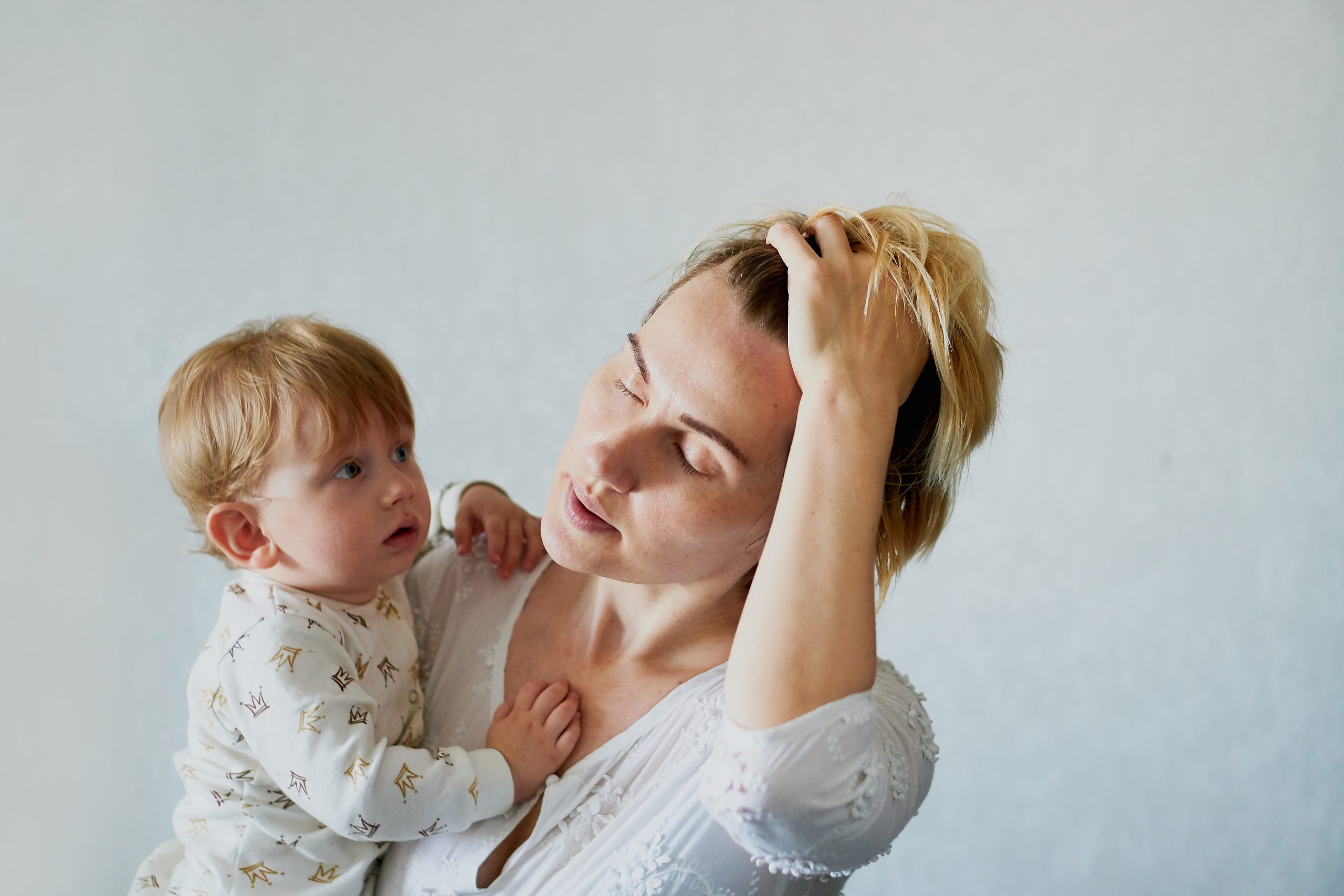 tired young woman holding a baby boy in her arms