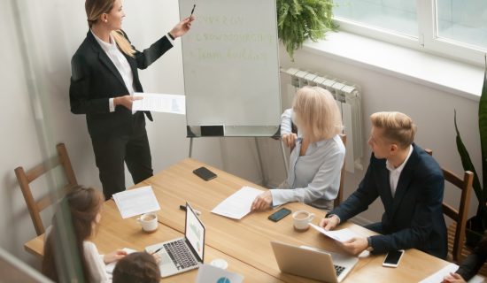 Businesswoman leader giving presentation explaining team goals a Businesswoman ceo boss in suit presenting corporate strategy pointing on flip chart at group meeting, business coach leader giving presentation explaining team goals in conference room at training