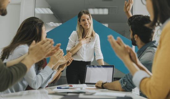 Pretty female team leader talking with mixed race group of people in the small startup office